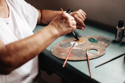 A senior artist engaged in painting at a studio in Buenos Aires.