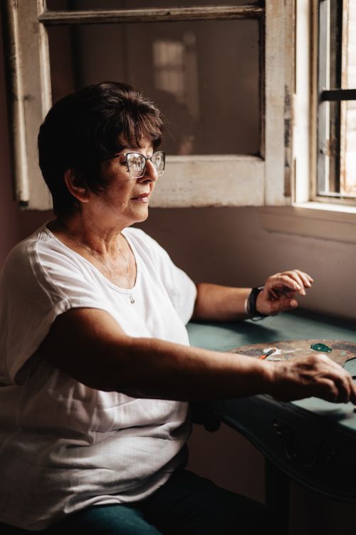 Free A senior woman sitting by a window, basking in natural sunlight in Buenos Aires. Stock Photo