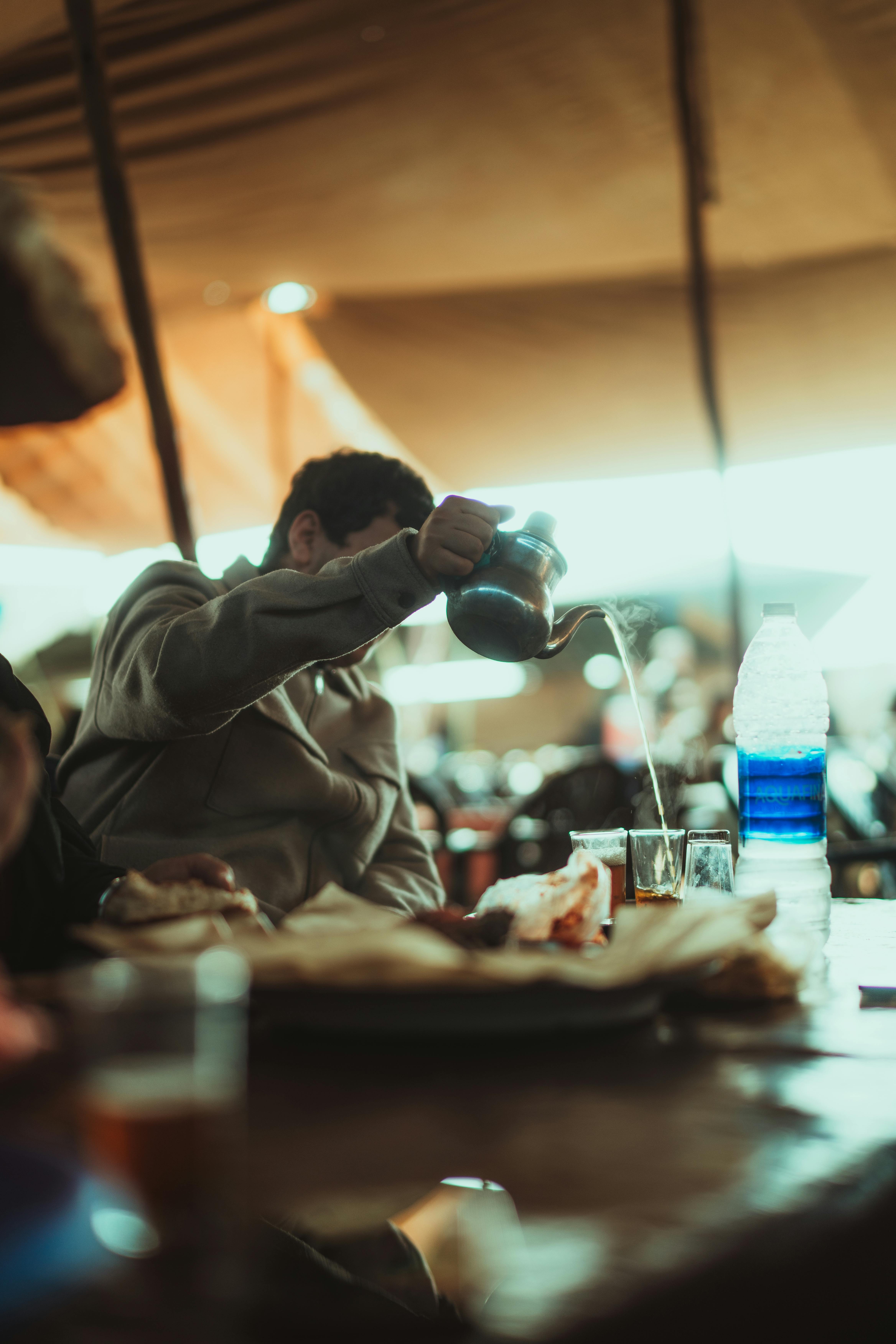 Zadarmo Muž nalieva čaj v útulnom, rustikálnom stane s teplým osvetlením. Fotka z fotobanky