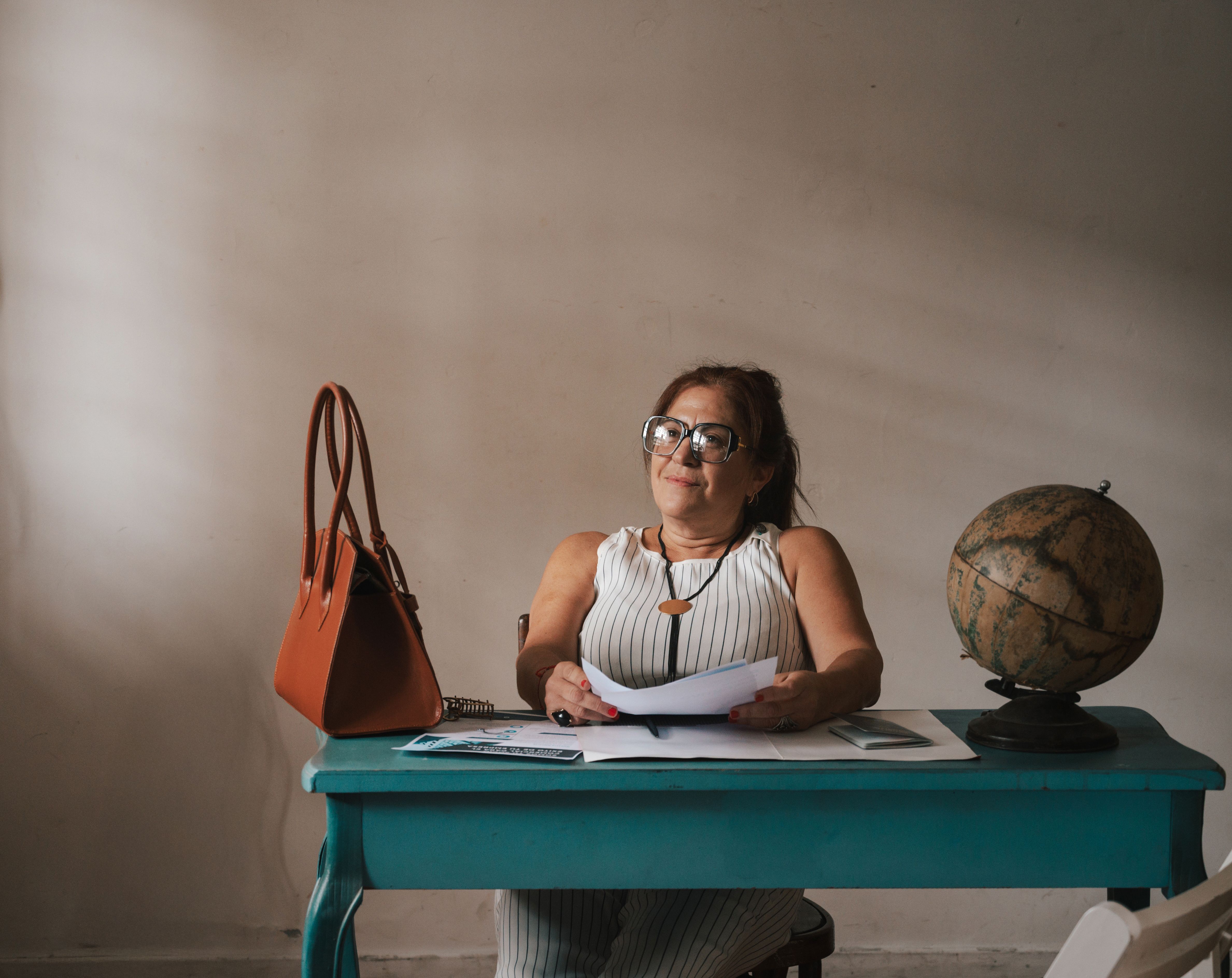 jeune femme stressée regardant des documents de refus de visa sur une table basse