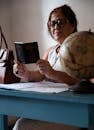 Woman Reads Passport at Home Desk with Globe