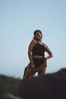 Cheerful woman posing on a beach during twilight, exuding confidence and happiness.