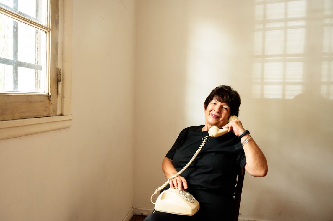 Una mujer mayor sonriente hablando por teléfono en una habitación luminosa.