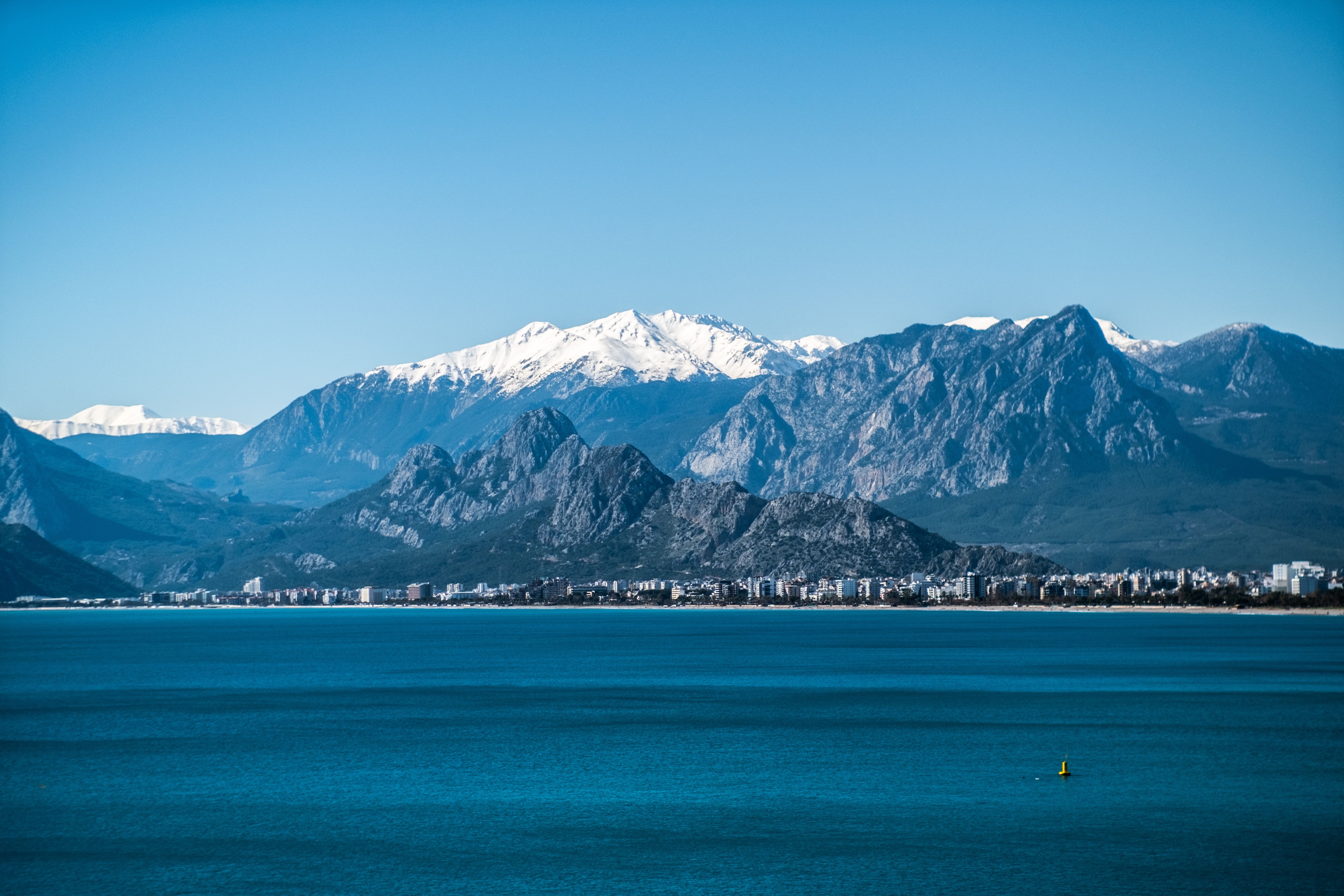 Scenic View of Coastal City with Snowy Mountains · Free Stock Photo