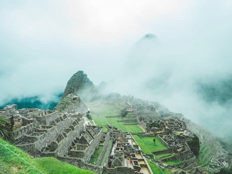 Aerial view of Machu Picchu shrouded in mist and clouds, capturing its ancient allure.