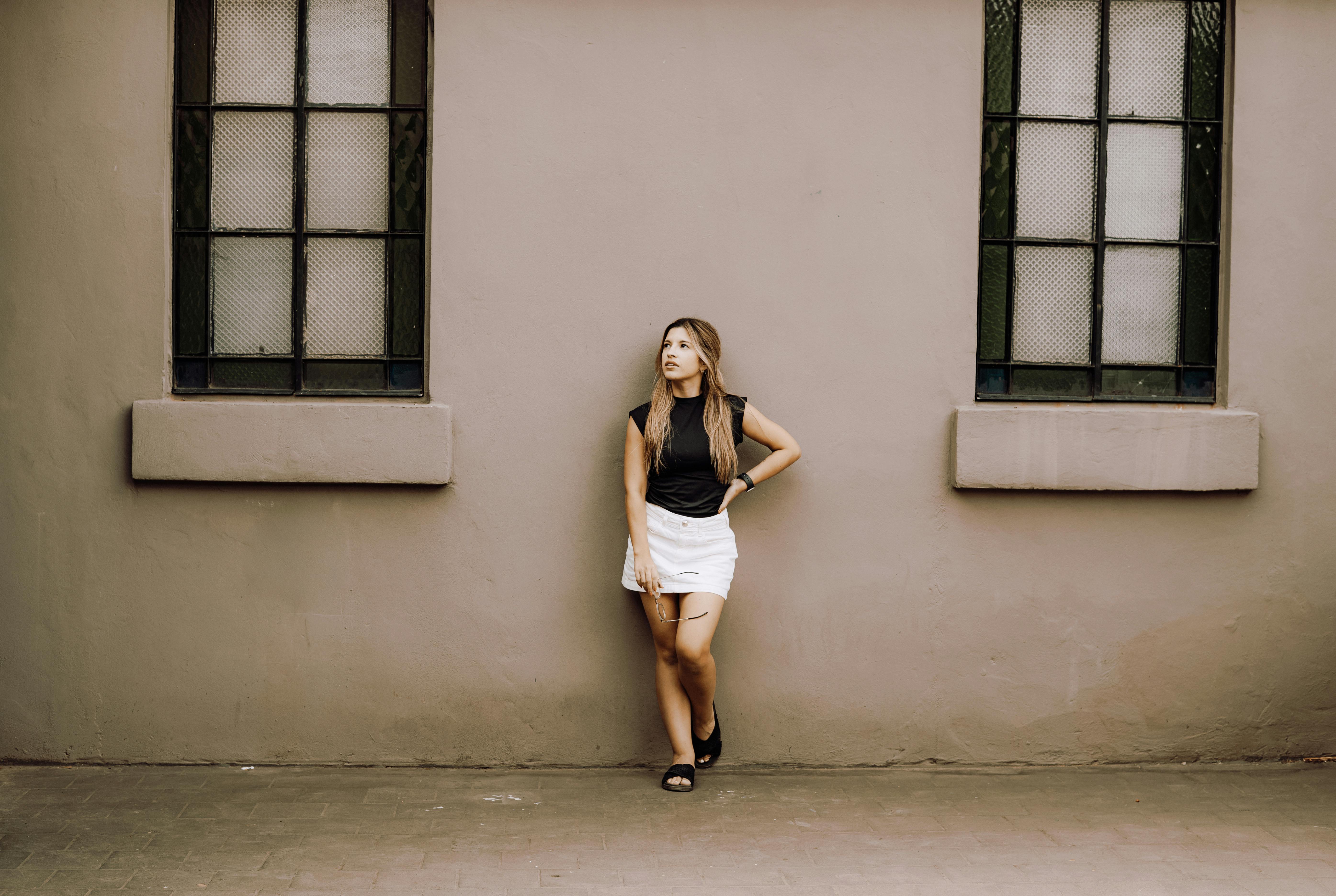 ingyenes Egy divatos fiatal nő egy falnak támaszkodik Buenos Airesben, Argentínában, magabiztosságot és stílust sugározva. Tökéletes modern városi portré. Stockfotó