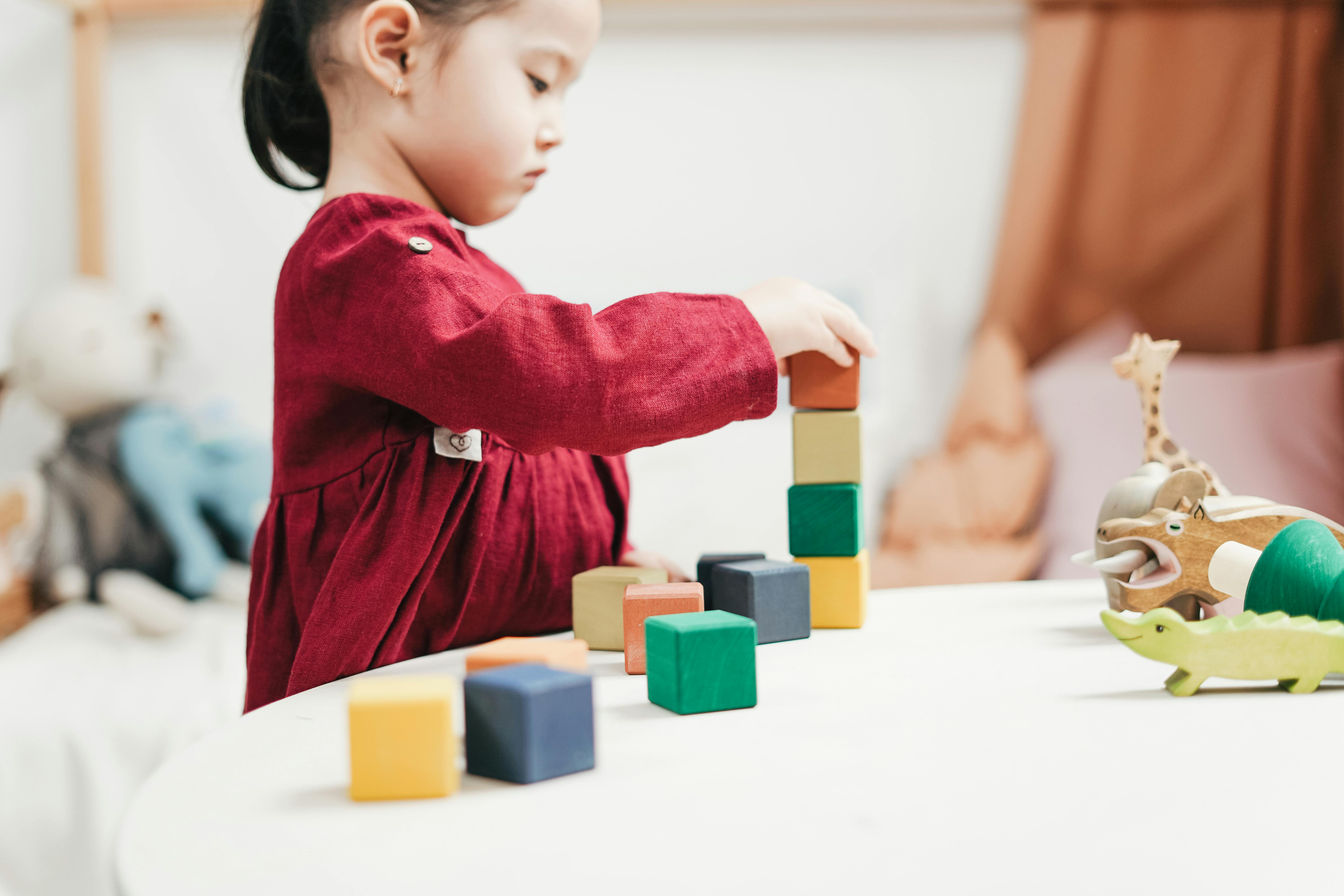 girl in red dress playing blocks