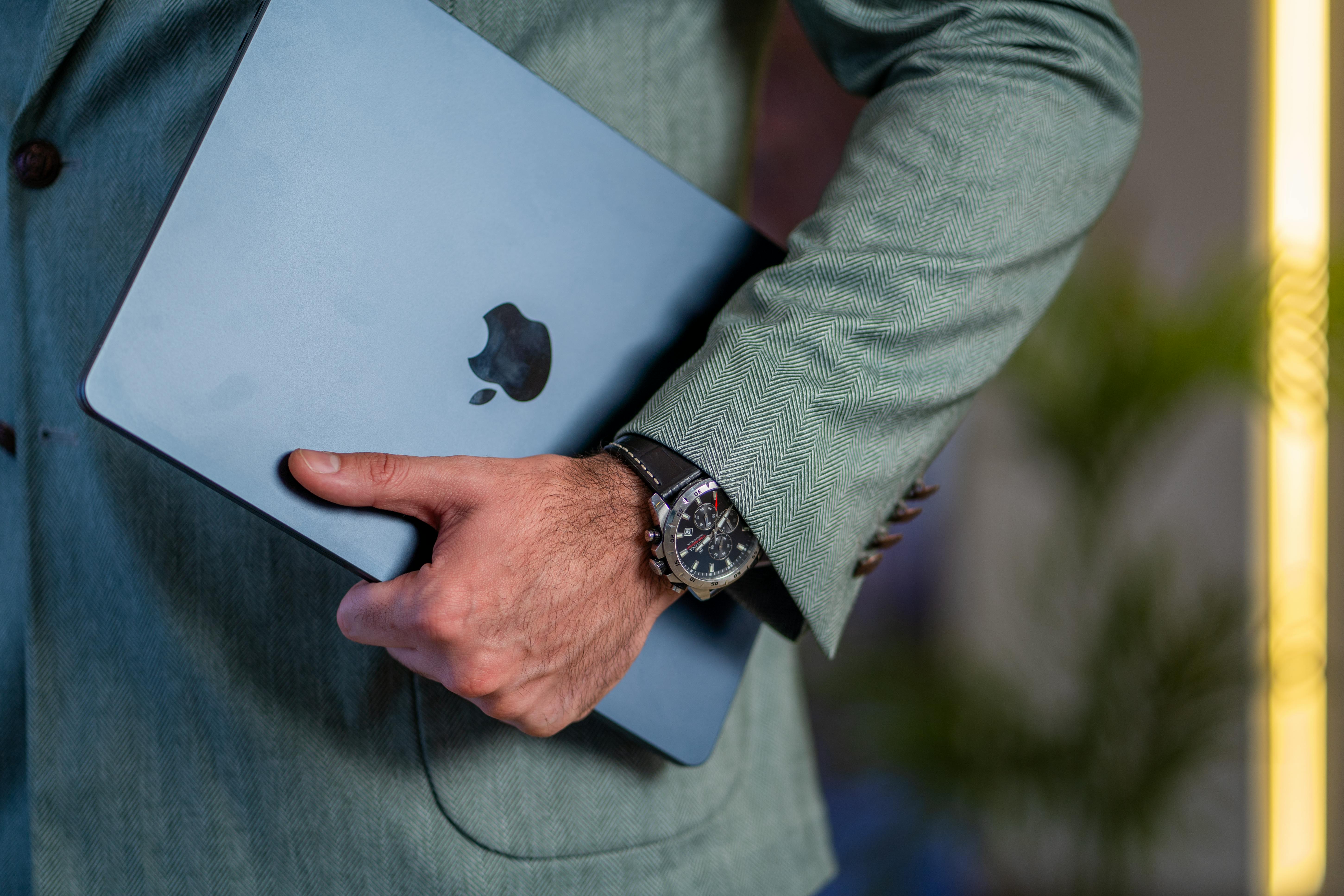 Close-up of a businessman holding a tablet in a stylish suit, showcasing elegance and modern technology.