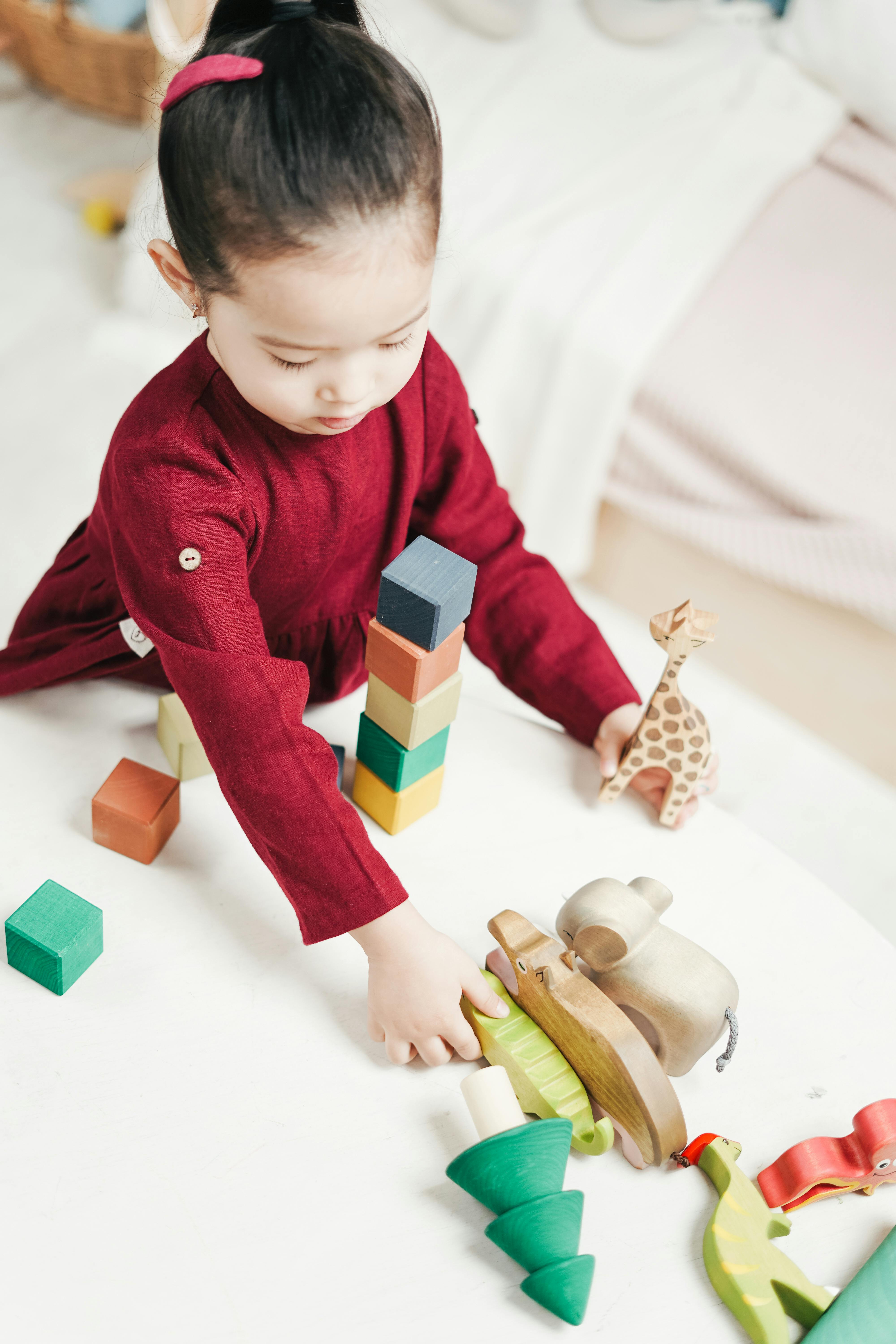 girl in red dress playing wooden blocks