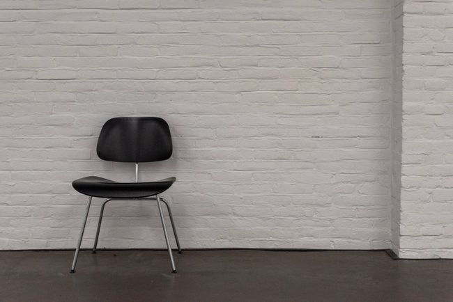 A dark moulded chair against a whitewashed brick wall — Jan van der Wolf on Pexels