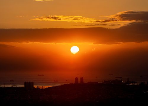 Free A breathtaking sunset over Manila Bay with ships silhouetted against the vibrant sky. Stock Photo