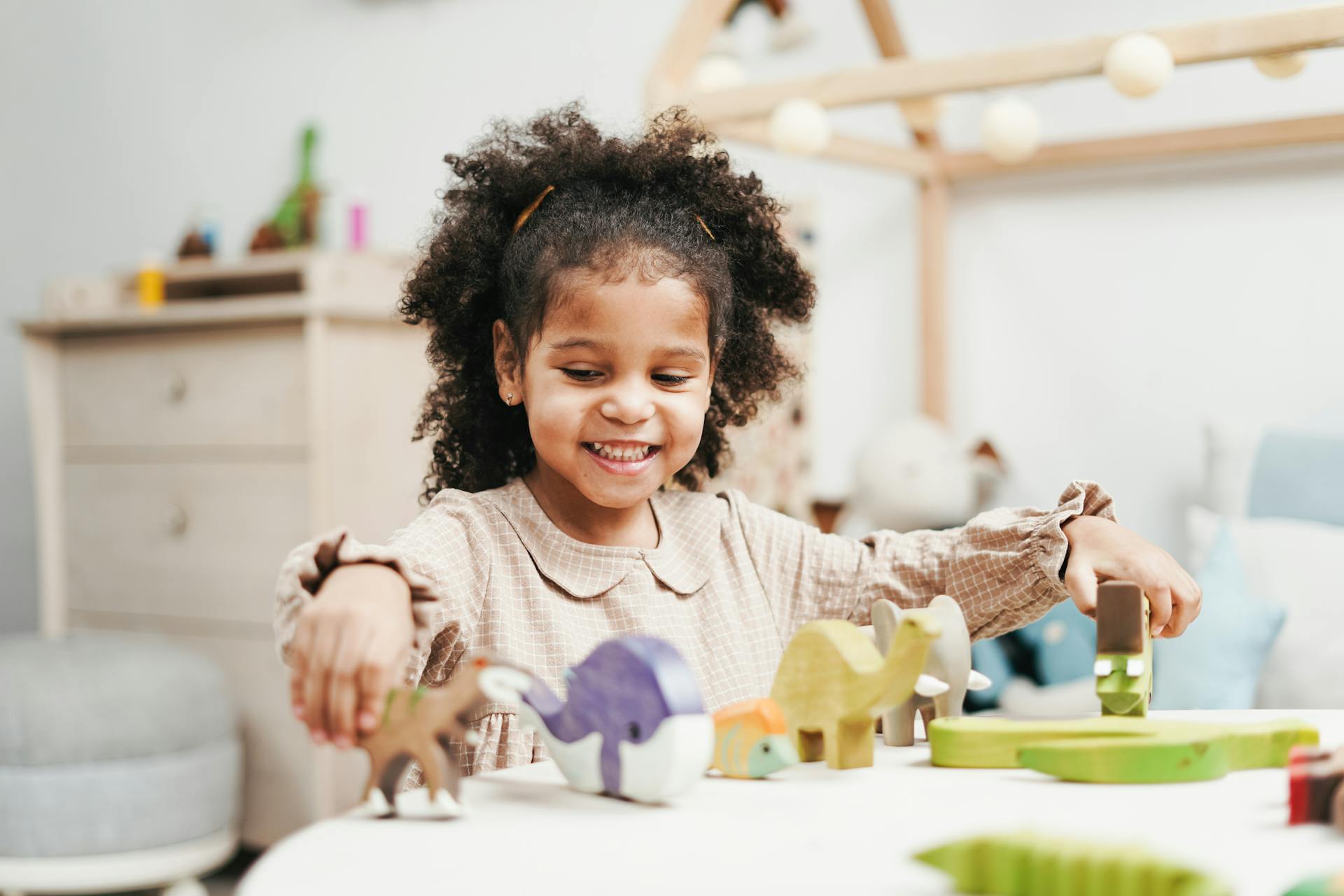 Selective Focus Photo of Smiling Young Girl Playing with Wooden Toys on White Table