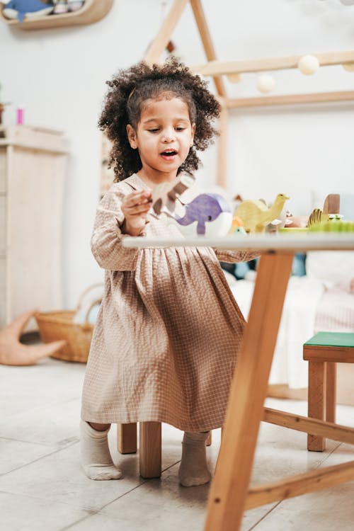 Free  Selective Focus Photo of Young Girl Playing with Wooden Toys on White Table Stock Photo