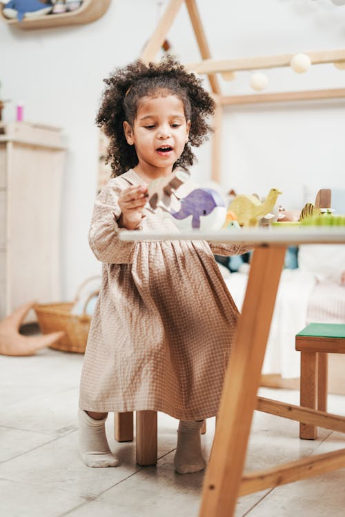  Selective Focus Photo of Young Girl Playing with Wooden Toys on White Table