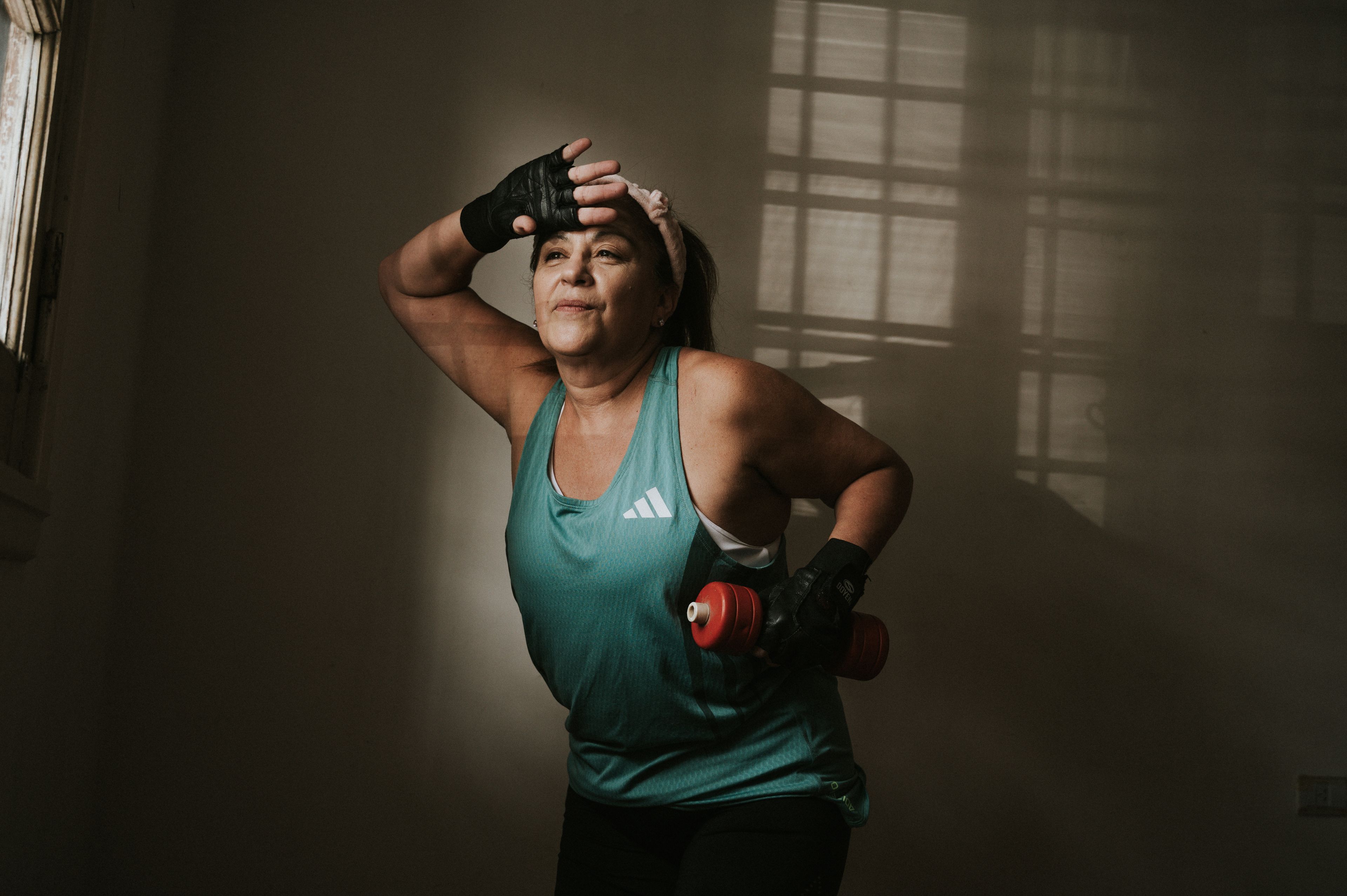 Middle-aged woman working out with a dumbbell indoors. Fitness and healthy lifestyle concept.