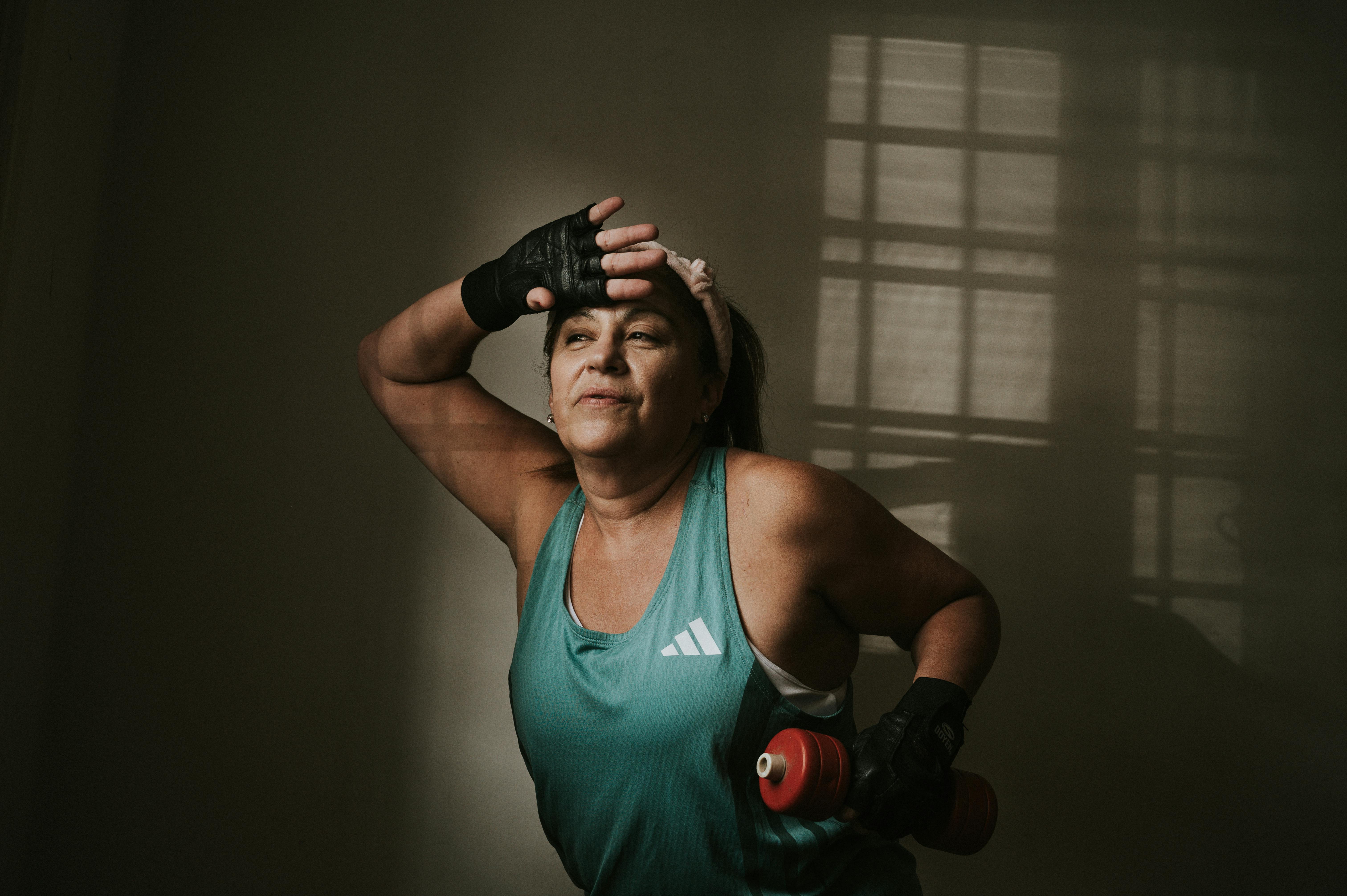 免費 一位身穿運動服的中年婦女手持啞鈴，在室內專注地鍛鍊。 圖庫相片