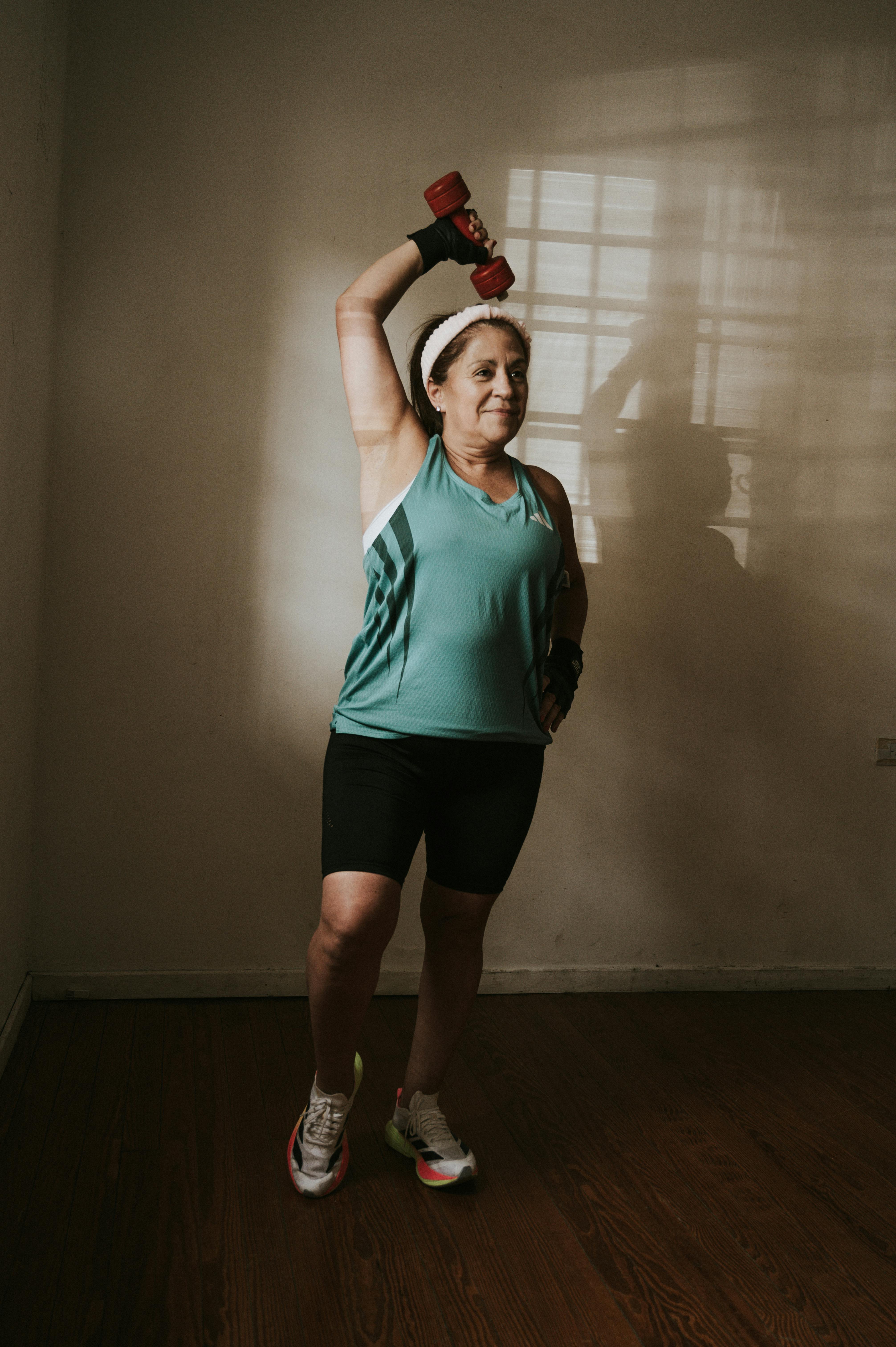 Senior woman exercising indoors lifting a dumbbell, promoting health and fitness at home.