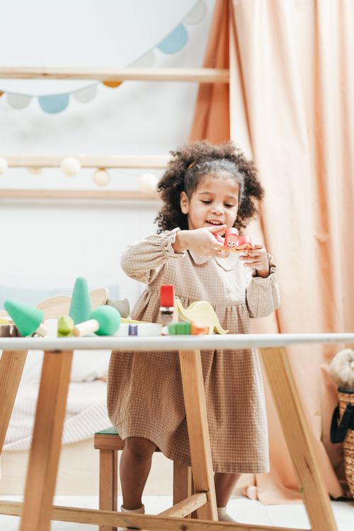 Free Young girl enjoys playing with colorful wooden toys in a bright indoor playroom. Stock Photo