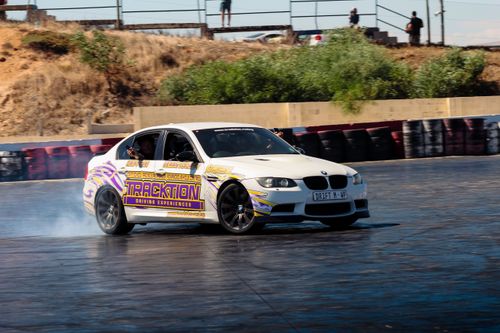 Free A white car performs a thrilling drift at an outdoor track, showcasing skill and excitement. Stock Photo