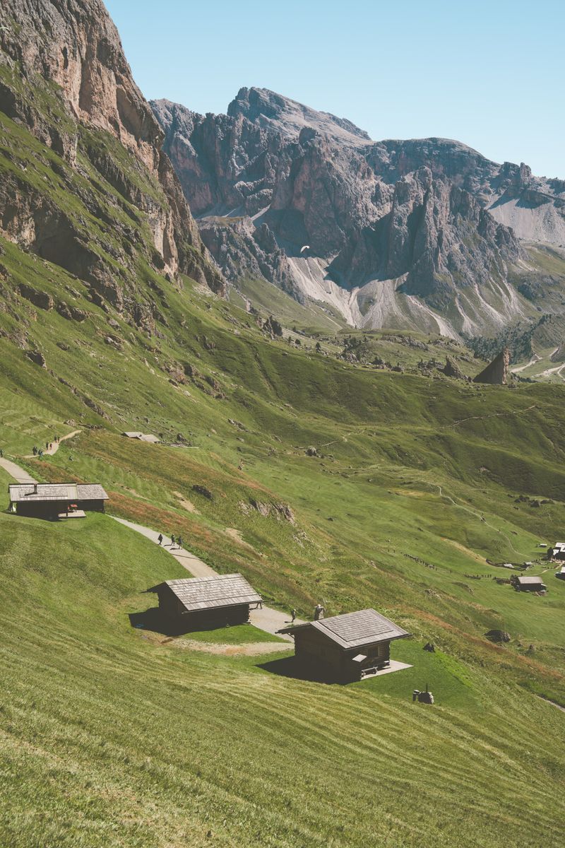 Picturesque alpine landscape in the Dolomites, featuring green meadows and rustic mountain cabins.