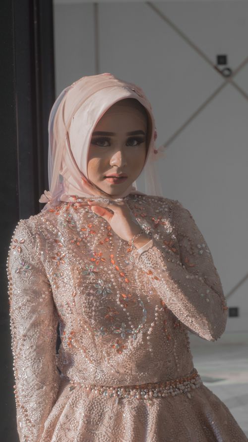 Free An Indonesian woman in a detailed, embellished dress, stands gracefully in soft lighting. Stock Photo