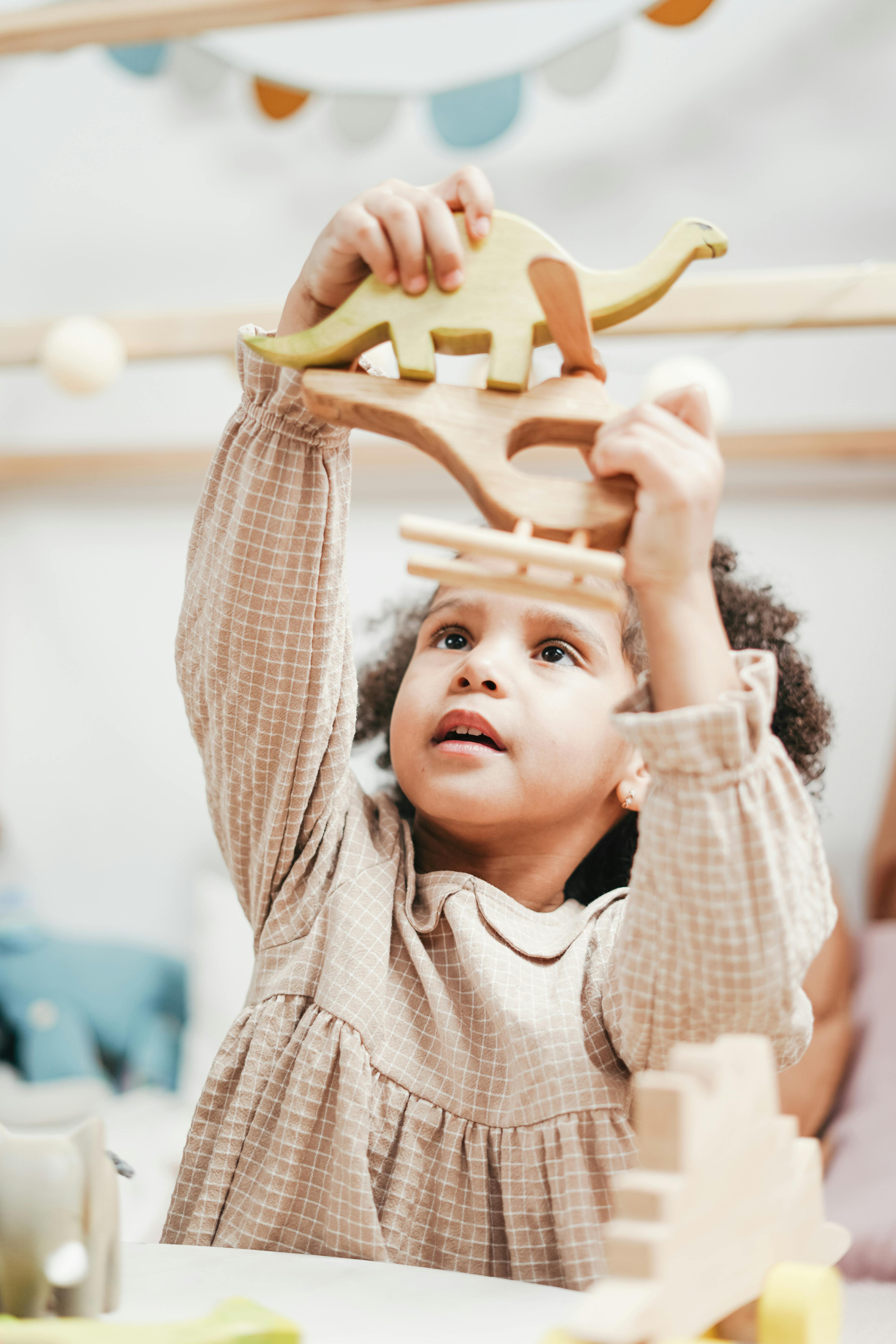 girl in white and brown stripe hoodie raising her hands with toys