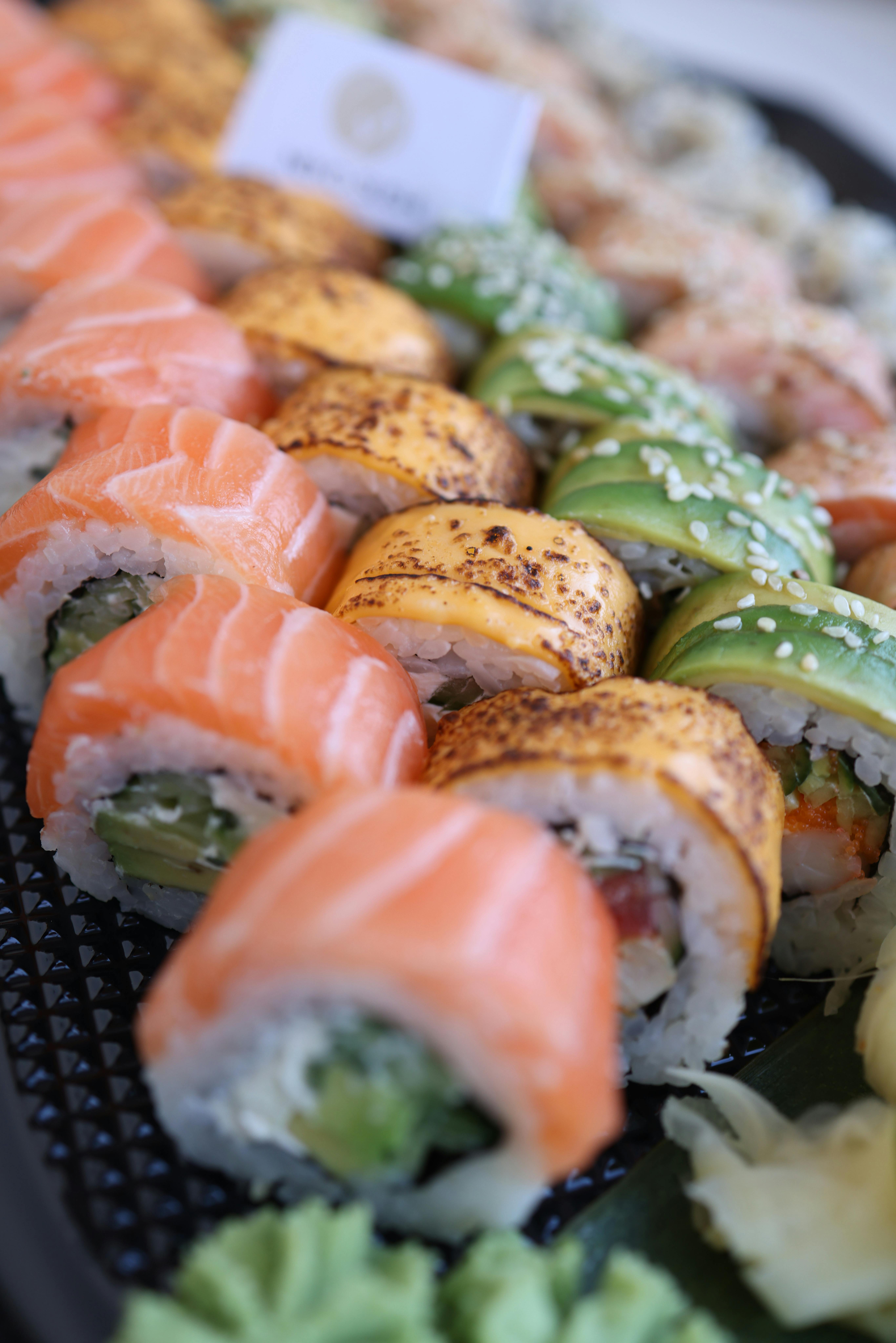 무료 연어, 아보카도 등을 포함한 신선한 재료로 만든 다양한 종류의 스시롤이 접시에 담겨 나옵니다. 스톡 사진