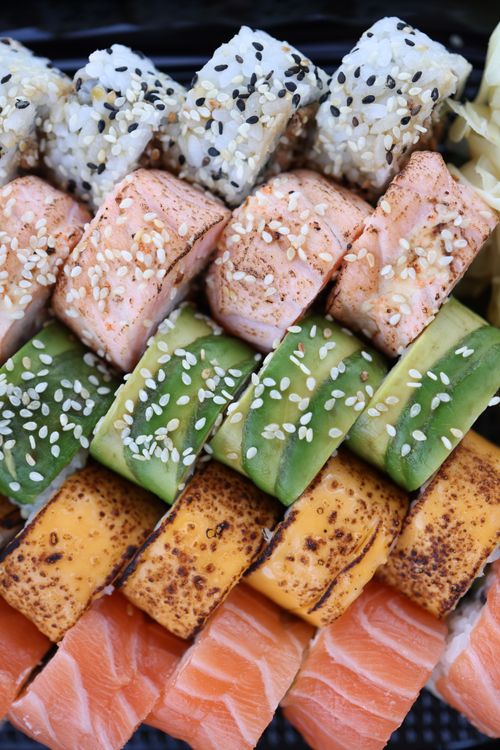 Free Colorful sushi rolls featuring salmon, avocado, and sesame seeds, beautifully arranged. Stock Photo
