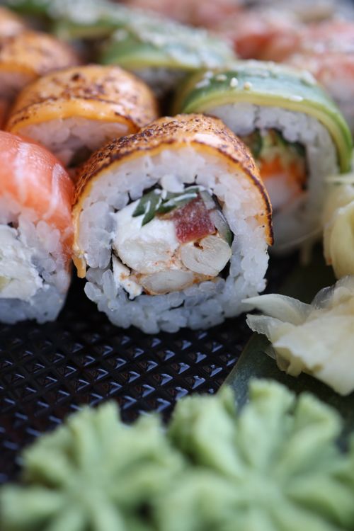 Free Delicious sushi rolls with various fillings, topped with salmon, avocado, and spices. Stock Photo