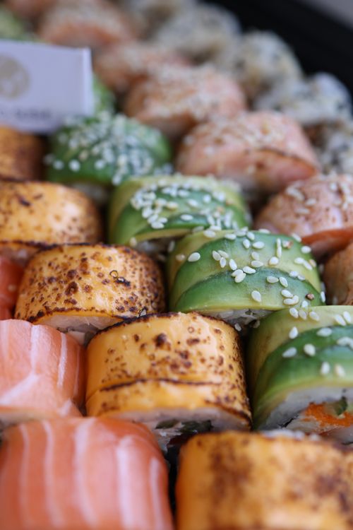 Free Close-up of assorted sushi rolls with avocado and salmon, topped with sesame seeds. Stock Photo