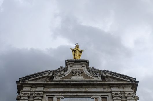 A golden statue atop the Basilica facade in Assisi, Italy.