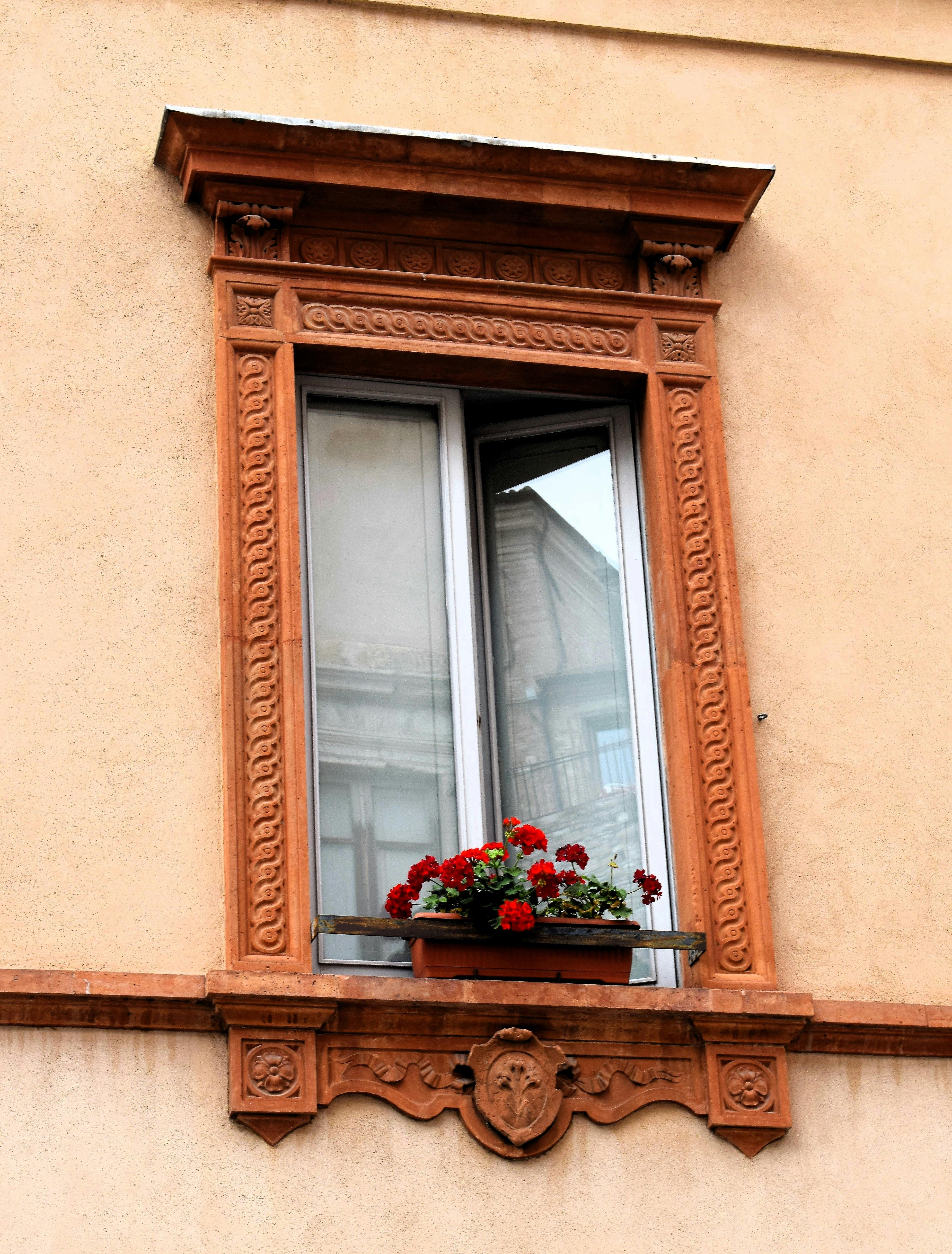Zadarmo Zdobený okenný rám so žiarivými kvetmi v Assise v Umbrii, ktorý predstavuje taliansku architektúru. Fotka z fotobanky