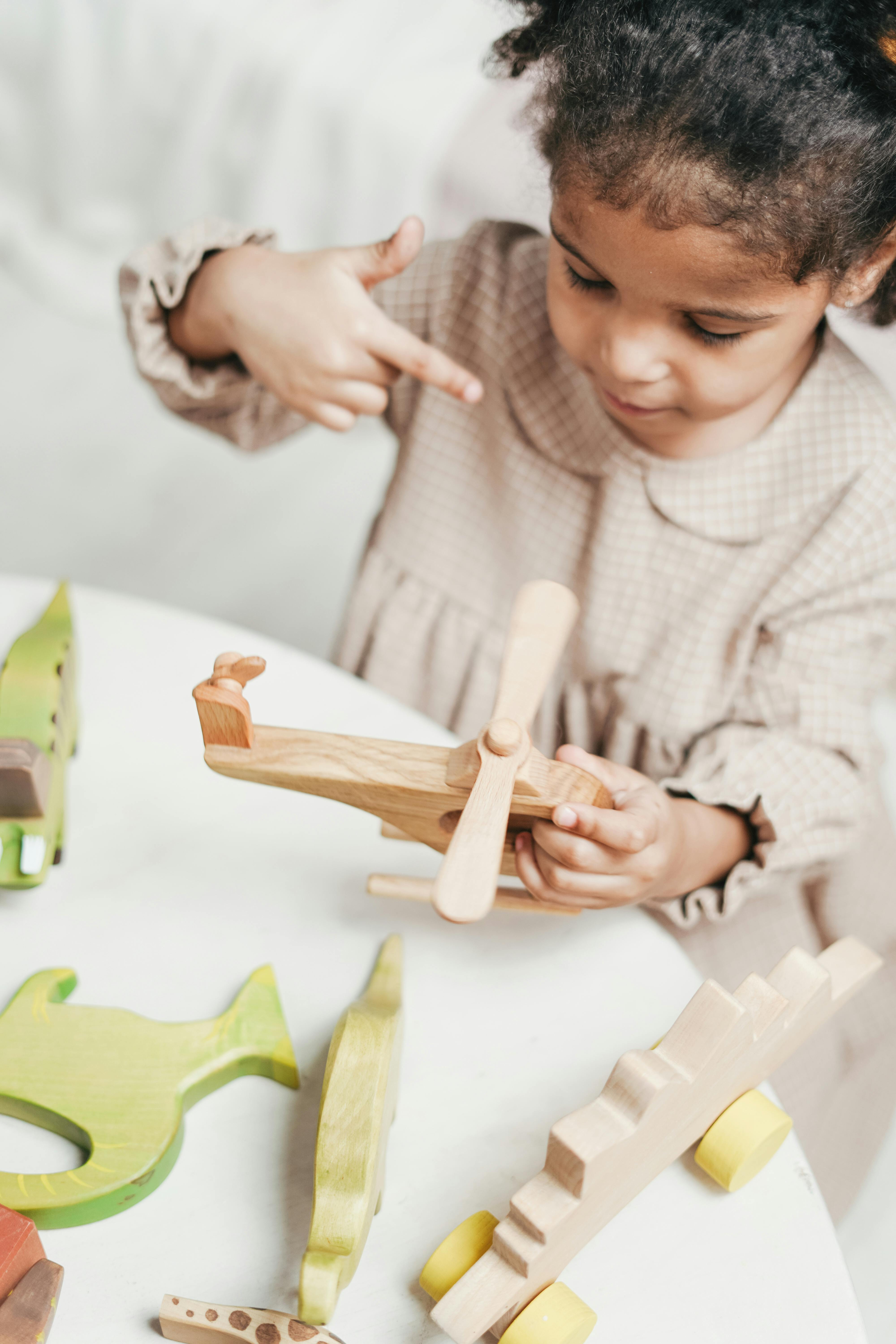 toddler is playing a wooden airplane