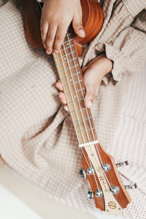 Person Playing Brown Ukelele 