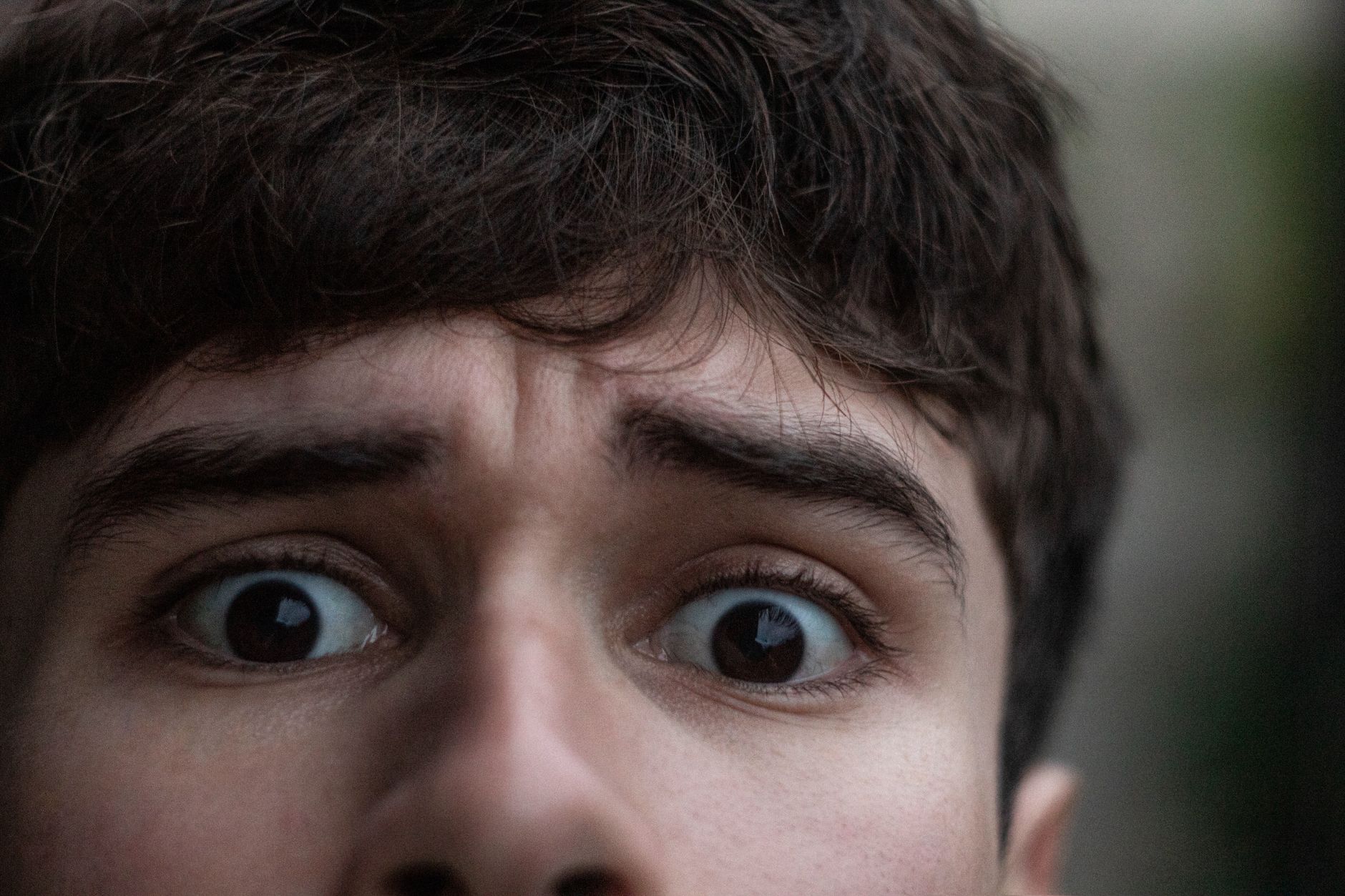 Close-up of a young man's face showing surprise, with wide eyes and raised eyebrows.