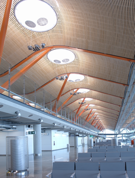 Wide interior view of modern architectural design at Madrid Barajas Airport with empty seats.