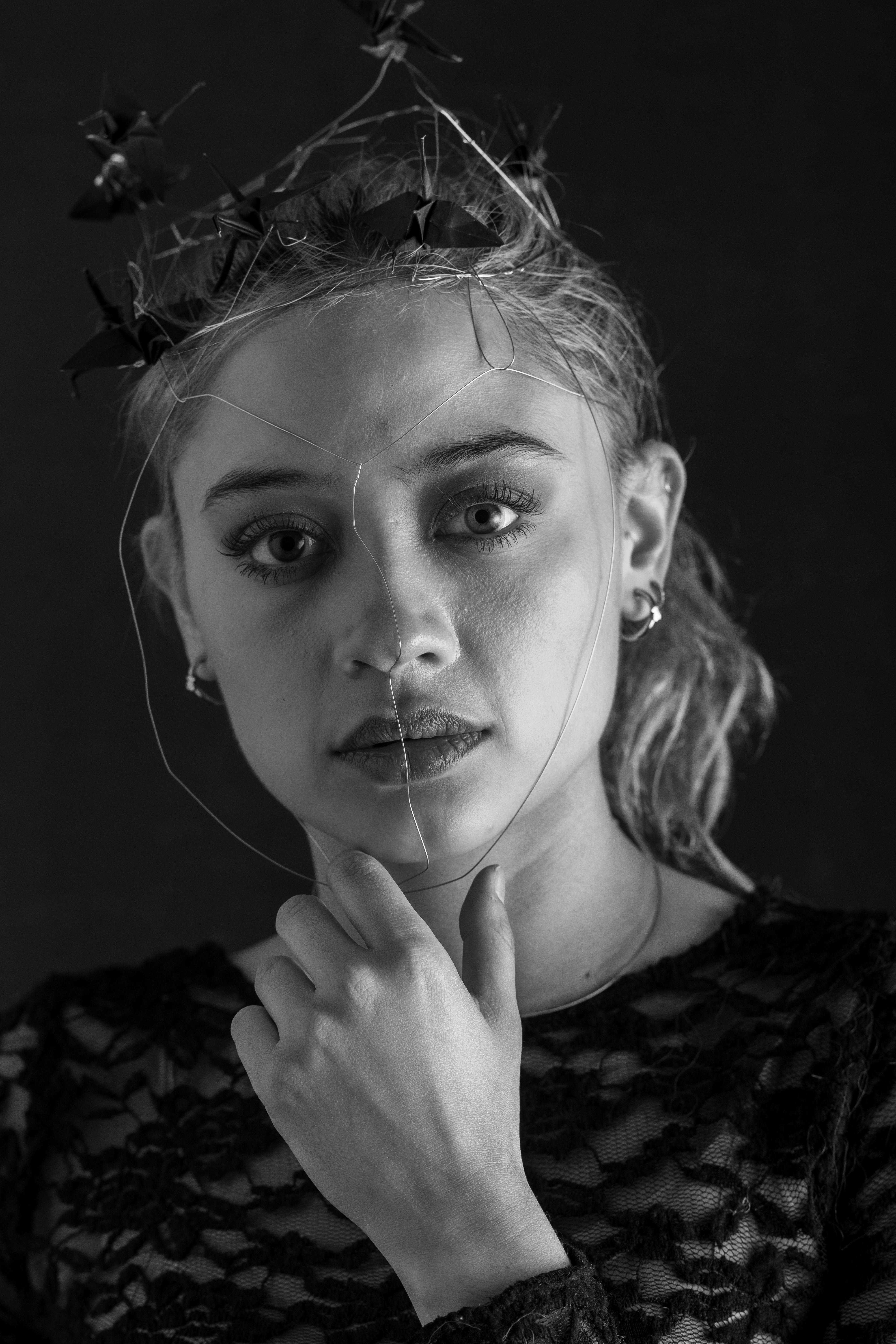 ingyenes Fekete-fehér portré egy dróthálóból készült fejdíszt viselő nőről, amely nagy kontrasztú esztétikát áraszt. Stockfotó