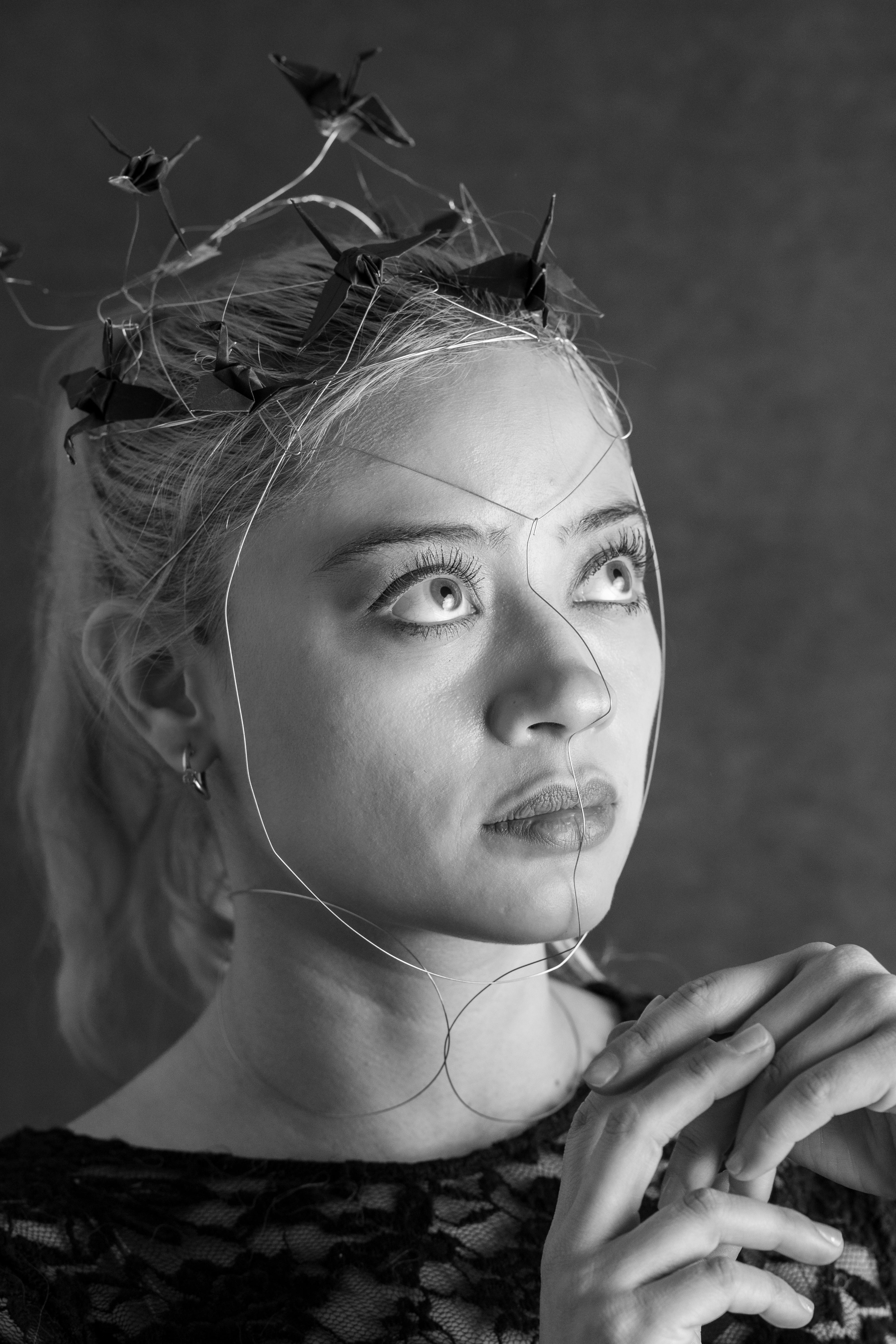 ingyenes Fekete-fehér portré egy mexikóvárosi nőről, aki fémhálóból készült origami fejdíszt visel, és önvizsgálatot sugároz. Stockfotó