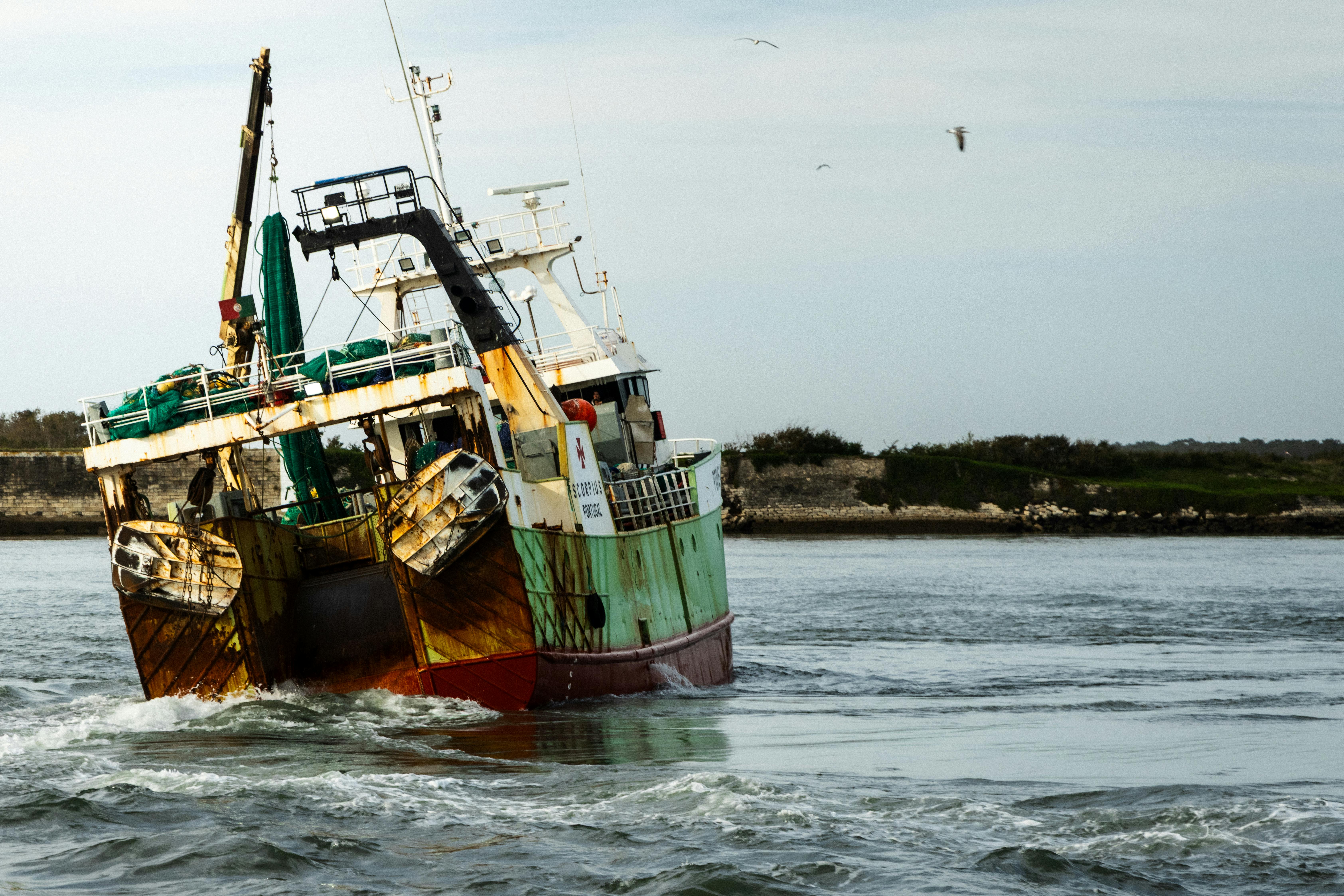 Zadarmo Živá rybárska loď sa plaví pozdĺž pobrežia pod otvorenou oblohou a zachytáva námornú krásu. Fotka z fotobanky