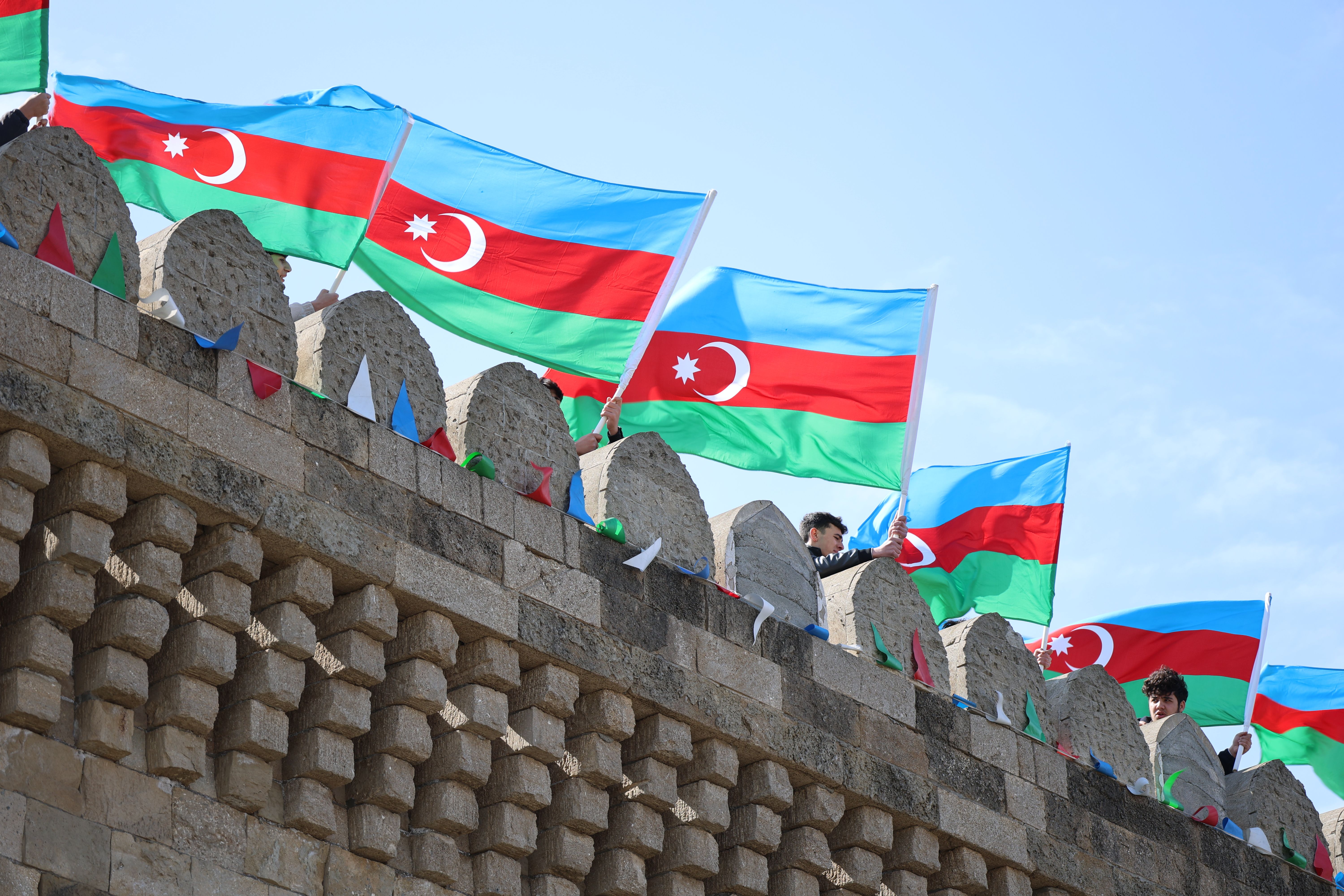 Gratuit Des drapeaux azerbaïdjanais aux couleurs éclatantes flottent sur une forteresse de pierre historique sous un ciel dégagé. Photos