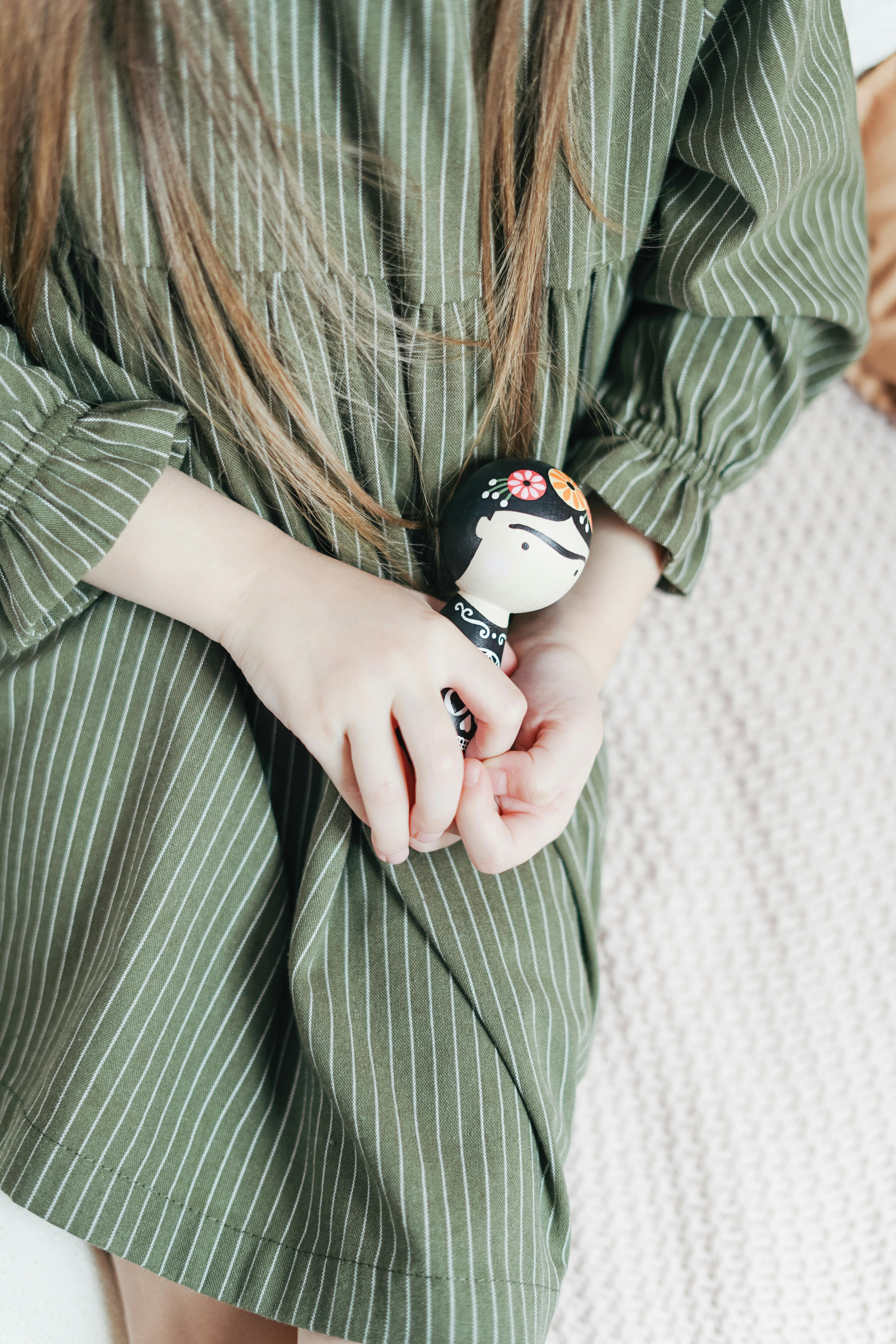 girl in green and white striped long sleeve shirt holding white and black ceramic mug