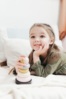photo of a happy kid lying on white bed