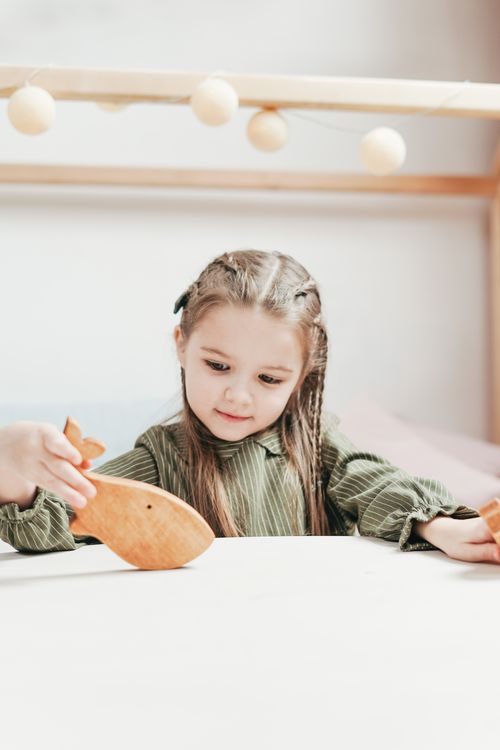 Free Young girl enjoying playtime indoors with wooden toys, expressing happiness and creativity. Stock Photo