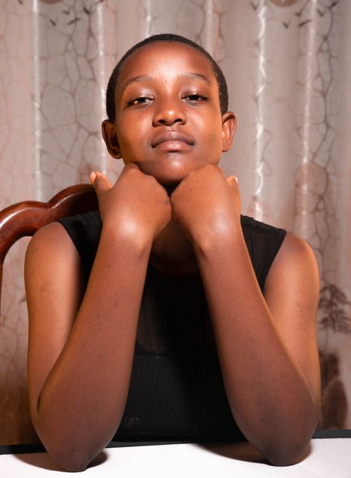 Free Portrait of a young adult resting their chin on hands indoors. Warm and contemplative mood. Stock Photo