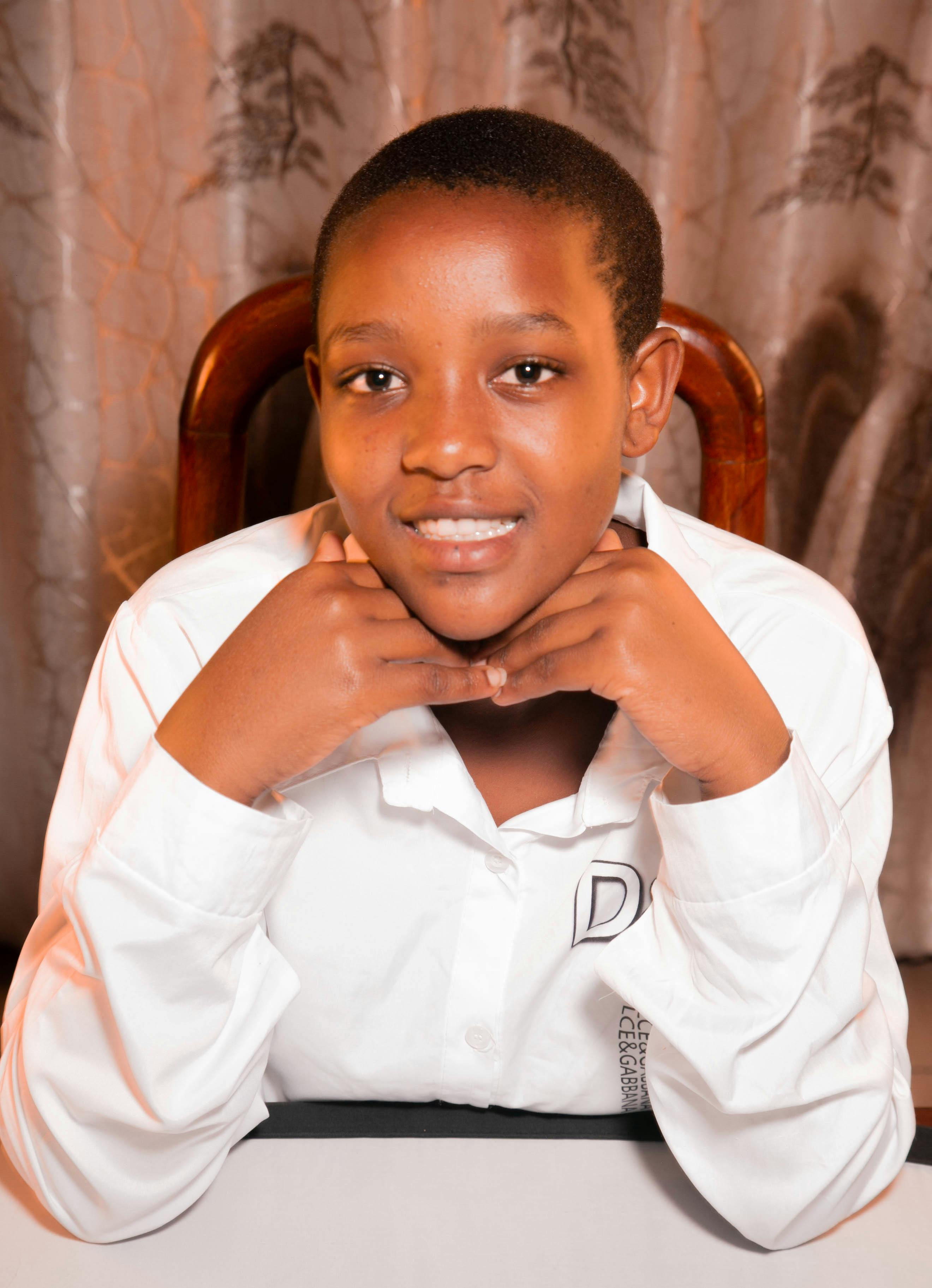 A young adult smiling while posing indoors, wearing a white shirt.
