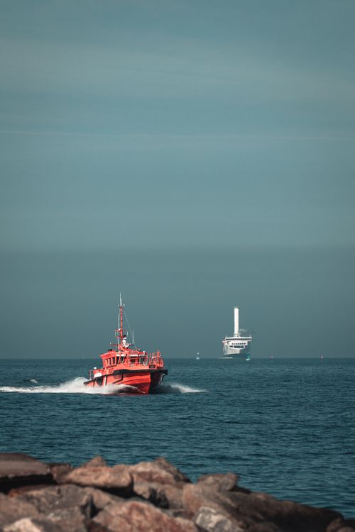 Free Red pilot boat navigating the Baltic Sea with distant wind turbine near Rostock, Germany. Stock Photo