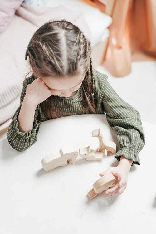 Free A Girl Playing a Wooden Toy at the Table Stock Photo