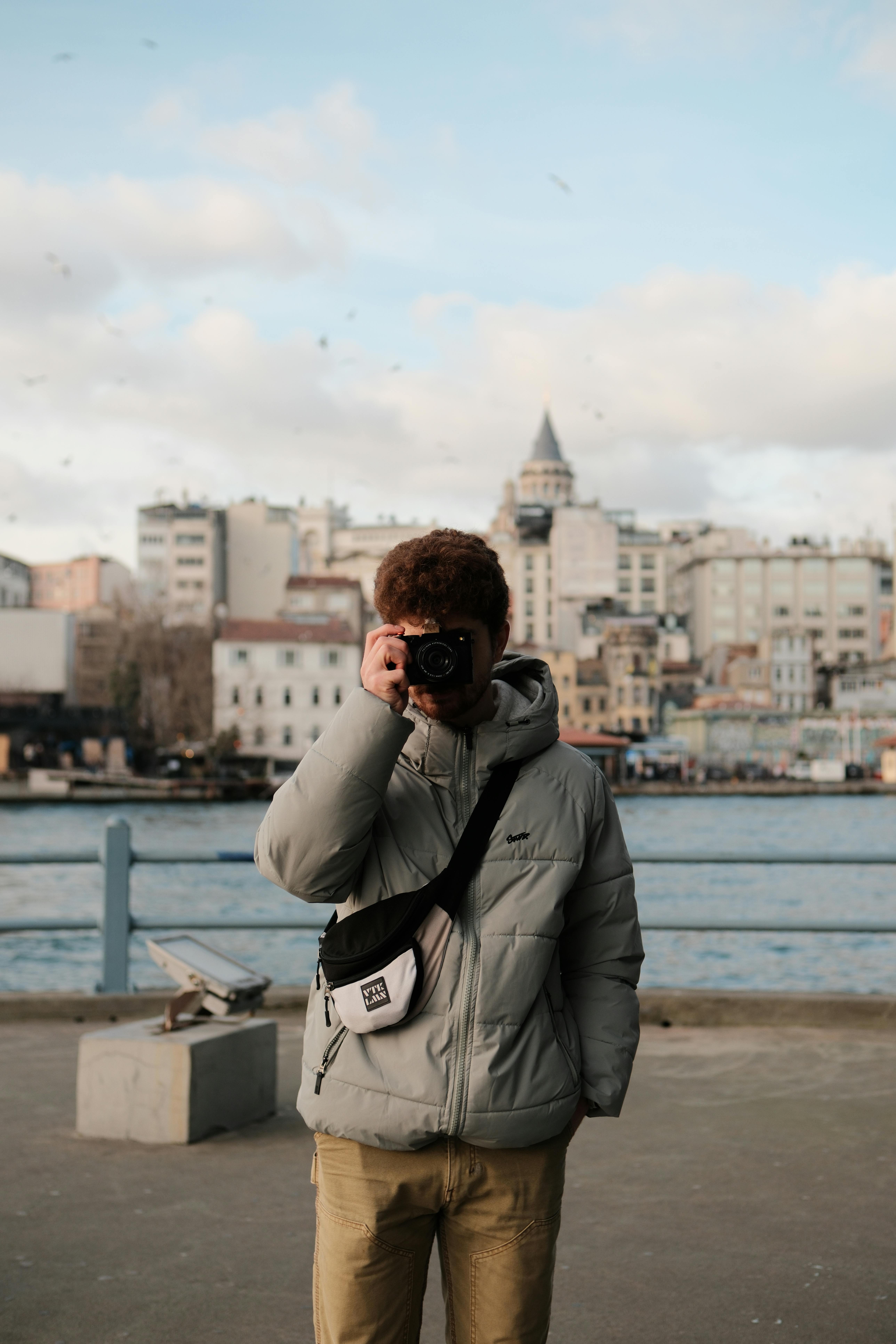Безкоштовне Фотограф стоїть на набережній, фотографуючи міський пейзаж з історичною архітектурою. стокове фото