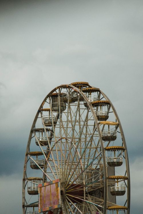 Free A large Ferris wheel set against a dramatic, cloudy sky, capturing a moody ambiance. Stock Photo