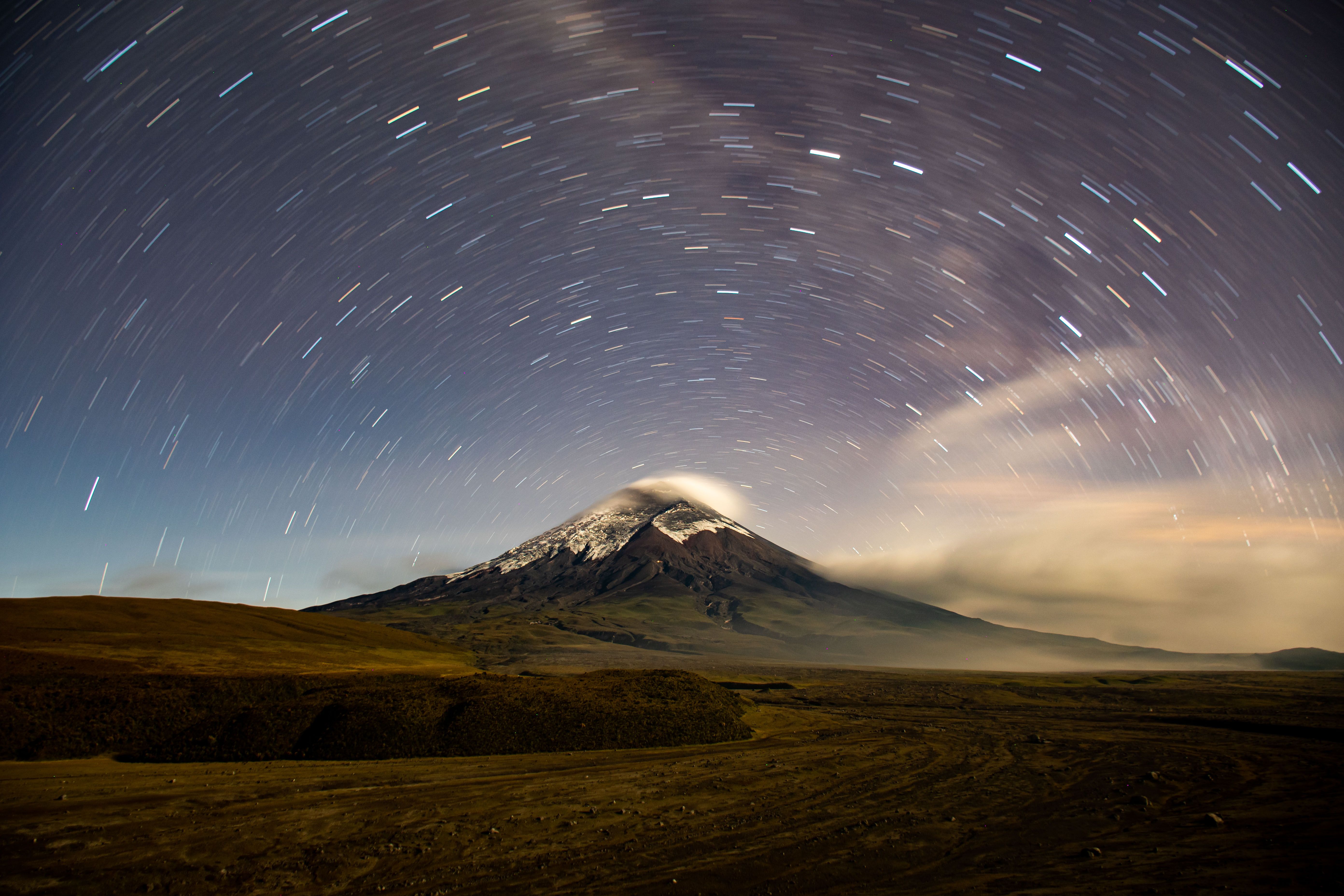 Stunning long exposure photograph capturing star trails over Cotopaxi Volcano at night.